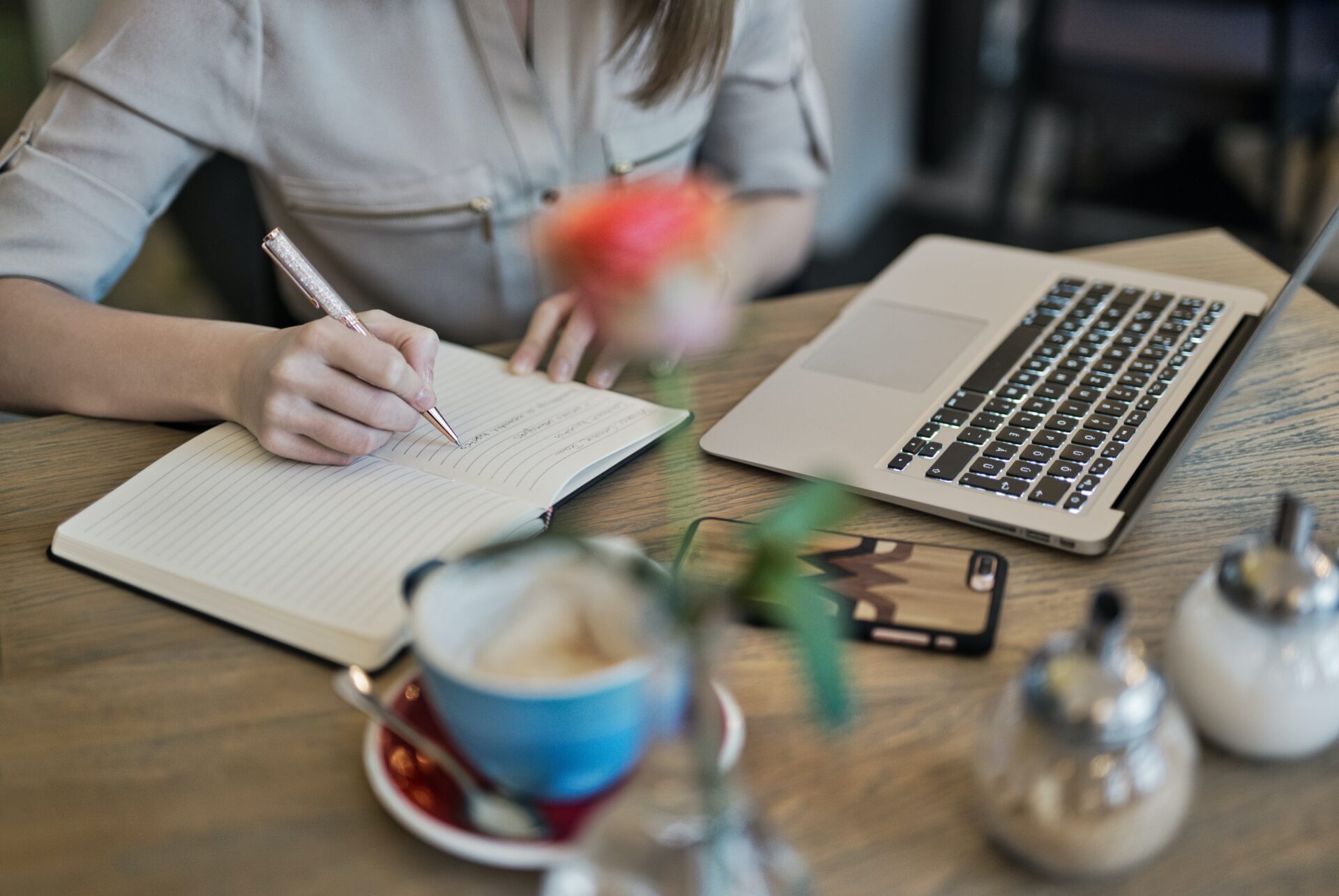 A women writing the content on notepad front of the laptop